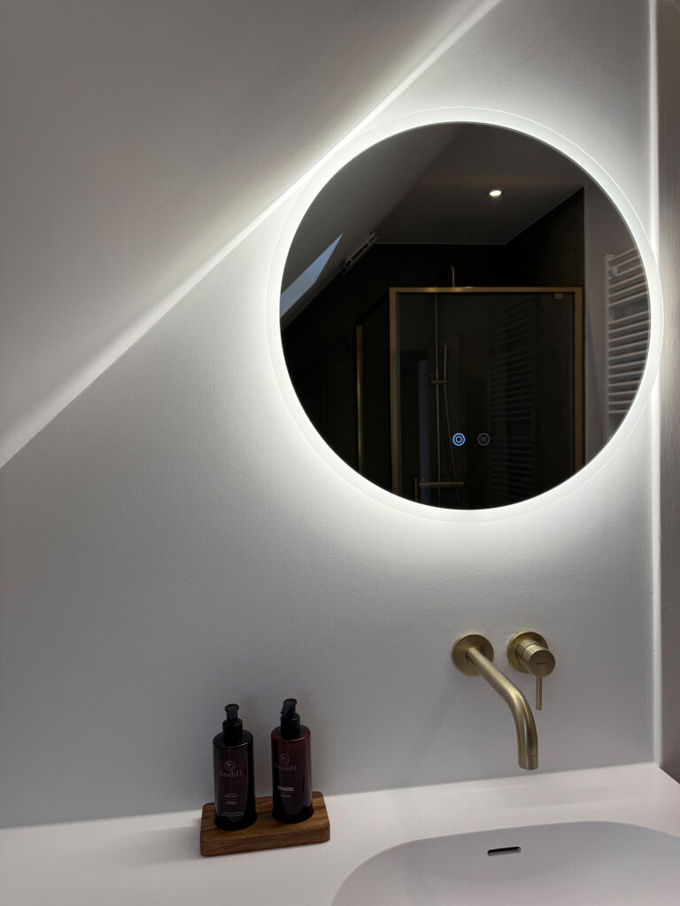 Ronde Senso-spiegel met indirecte led-verlichting boven wastafel in renovatie badkamer Brussel